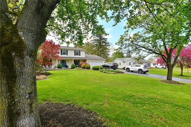 view of grassy yard featuring a garage and asphalt driveway