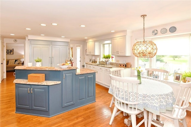 kitchen featuring a center island, a sink, white cabinets, light wood-style flooring, and recessed lighting