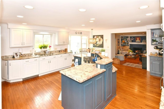 kitchen with a sink, white cabinetry, a kitchen island, light wood-style floors, and recessed lighting