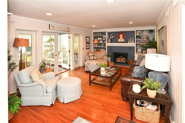 living area with ornamental molding, light wood-style flooring, a brick fireplace, recessed lighting, and built in features