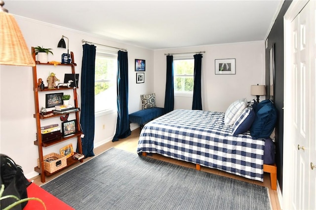 bedroom with ornamental molding, wood finished floors, and baseboards