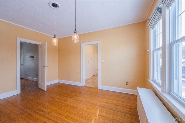 empty room featuring light wood-style flooring, baseboards, and crown molding