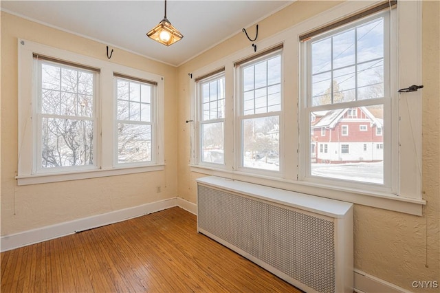 spare room featuring radiator, baseboards, ornamental molding, and light wood-style flooring