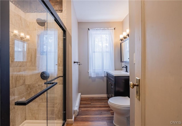 bathroom featuring a shower stall, vanity, wood finished floors, baseboard heating, and baseboards