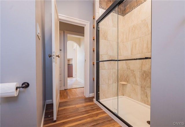 bathroom with a stall shower, wood finished floors, and baseboards