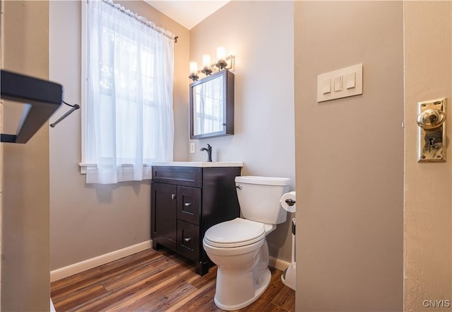 bathroom featuring baseboards, wood finished floors, toilet, and vanity