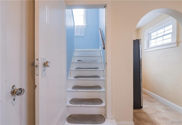 stairs featuring arched walkways and baseboards