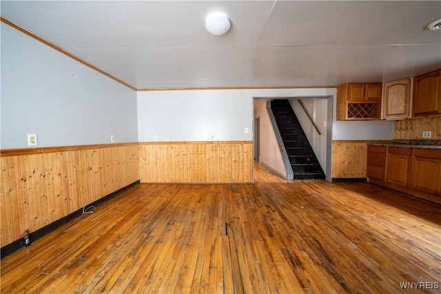 kitchen featuring hardwood / wood-style flooring, wainscoting, brown cabinets, and wooden walls