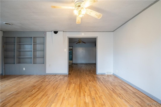 empty room with ceiling fan, wood finished floors, and baseboards
