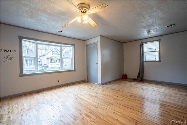 unfurnished room with a textured ceiling, light wood finished floors, a ceiling fan, and baseboards