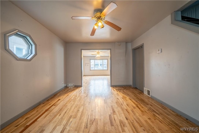 spare room with a ceiling fan, light wood-style floors, and baseboards