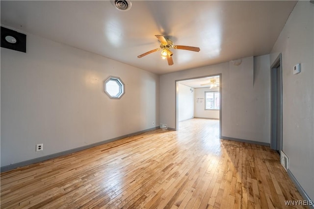 spare room featuring a ceiling fan, light wood-type flooring, and baseboards