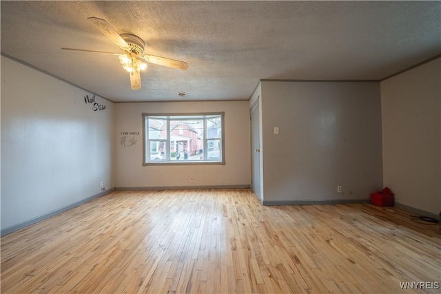 spare room featuring a textured ceiling, light wood-style floors, ceiling fan, and baseboards