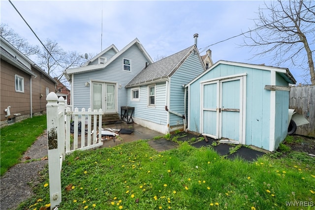 back of property with a shed, entry steps, an outdoor structure, and fence