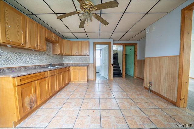 kitchen featuring a paneled ceiling, ceiling fan, wainscoting, and a sink