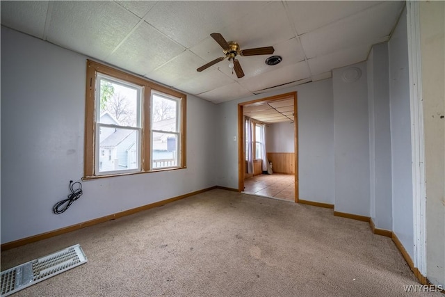 unfurnished room with carpet flooring, ceiling fan, healthy amount of natural light, baseboards, and a paneled ceiling