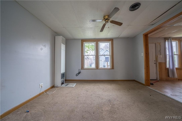 carpeted spare room featuring ceiling fan, plenty of natural light, and baseboards