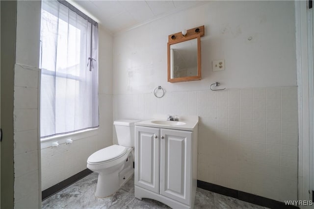 half bathroom with tile walls, toilet, vanity, and crown molding