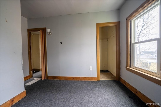 unfurnished bedroom featuring carpet floors, baseboards, and a walk in closet