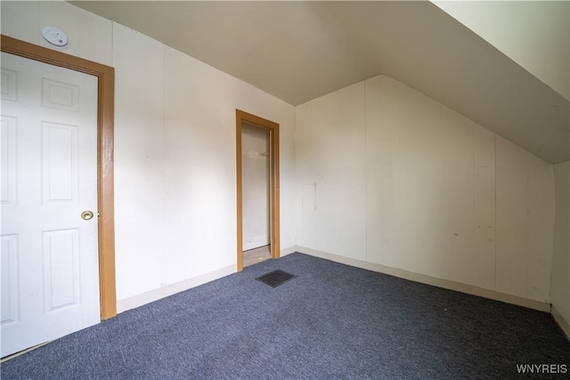 additional living space featuring dark colored carpet and vaulted ceiling