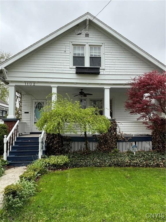 view of front facade with covered porch, ceiling fan, and a front lawn