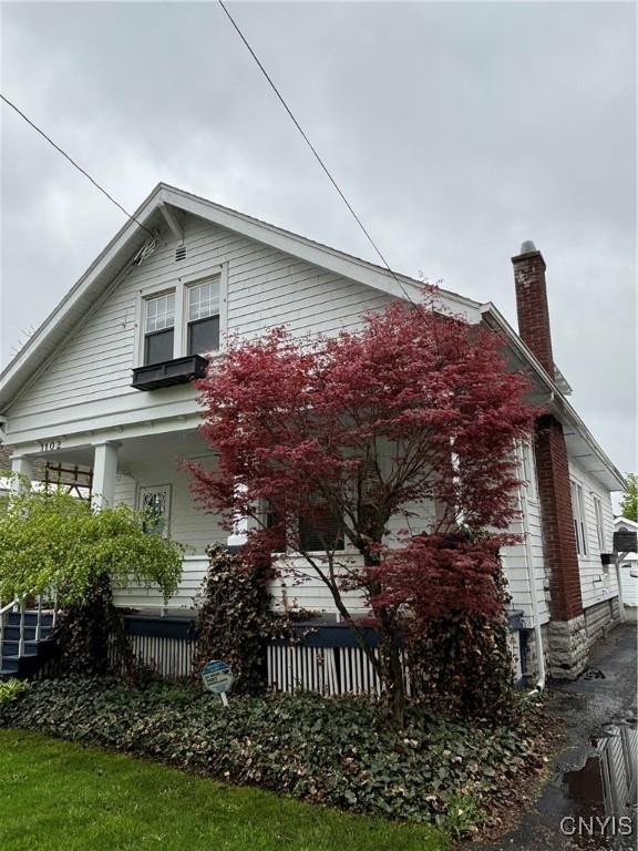 view of side of home featuring a chimney and a porch