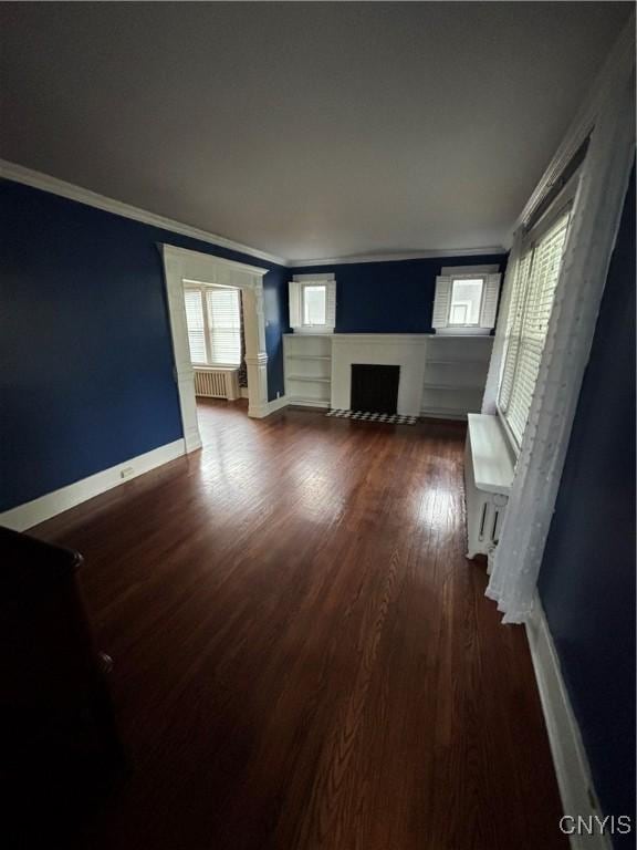 unfurnished living room with ornamental molding, wood finished floors, a fireplace with flush hearth, baseboards, and radiator heating unit