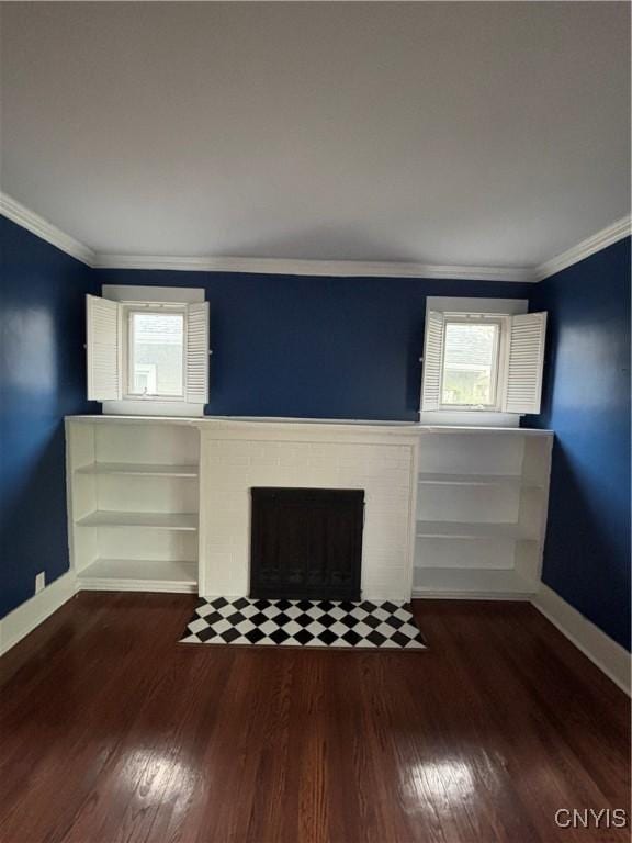 unfurnished living room featuring ornamental molding, a brick fireplace, baseboards, and wood finished floors