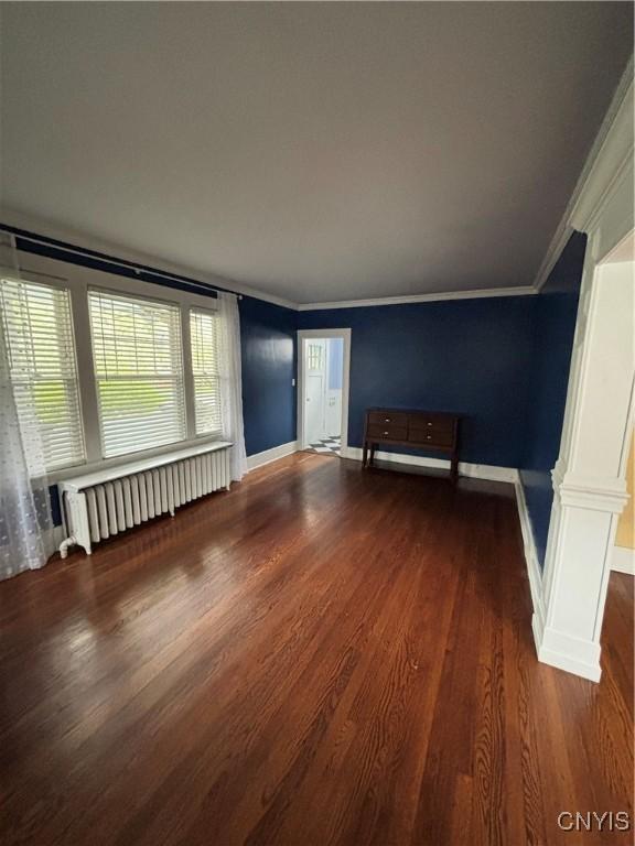 spare room with radiator, wood finished floors, ornamental molding, and baseboards