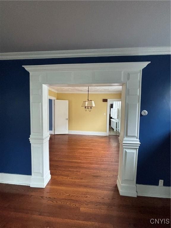 unfurnished dining area featuring crown molding, baseboards, and wood finished floors