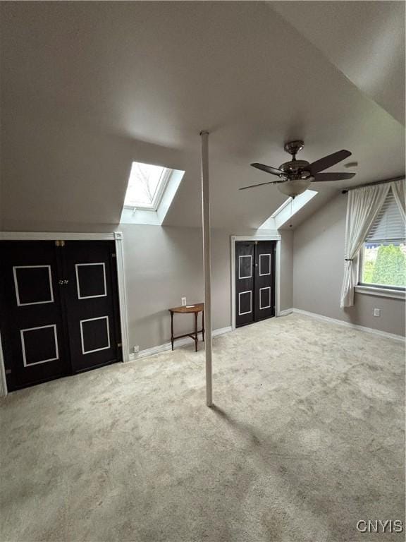bonus room with a skylight, lofted ceiling, carpet, ceiling fan, and baseboards