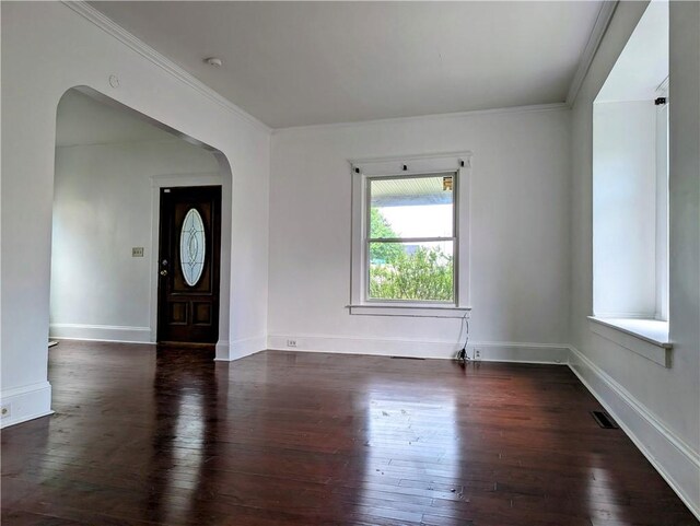 entryway featuring arched walkways, hardwood / wood-style flooring, ornamental molding, and baseboards