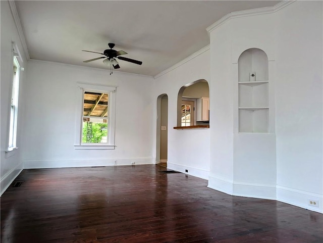 spare room with ceiling fan, wood finished floors, crown molding, arched walkways, and baseboards