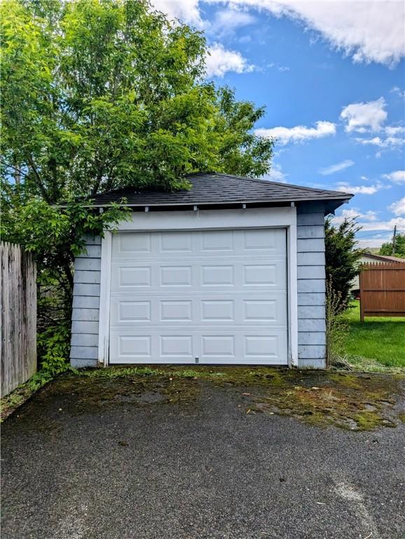 detached garage featuring fence and driveway