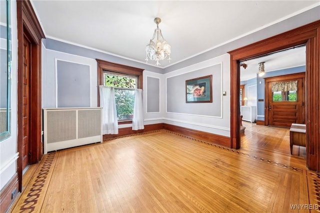 82 Clinton St, Tonawanda-City, NY 14150 - unfurnished dining area featuring radiator heating unit, a chandelier, plenty of natural light, wood-type flooring, and ornamental molding