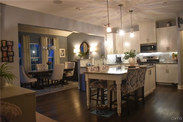 5546 Rolling Meadows Way, Camillus, NY 13031 - kitchen with stainless steel appliances, tasteful backsplash, dark wood-type flooring, a breakfast bar area, and white cabinetry