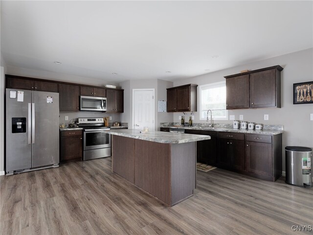 36395 Sarah Ln, Orleans, NY 13656 - kitchen featuring stainless steel appliances, dark brown cabinetry, wood finished floors, a kitchen island, and a sink
