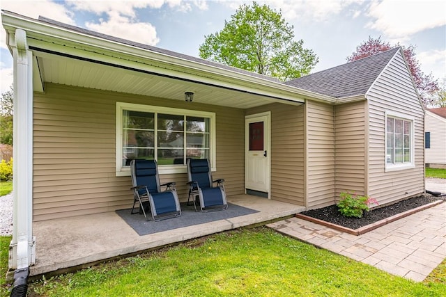 doorway to property with covered porch and a shingled roof