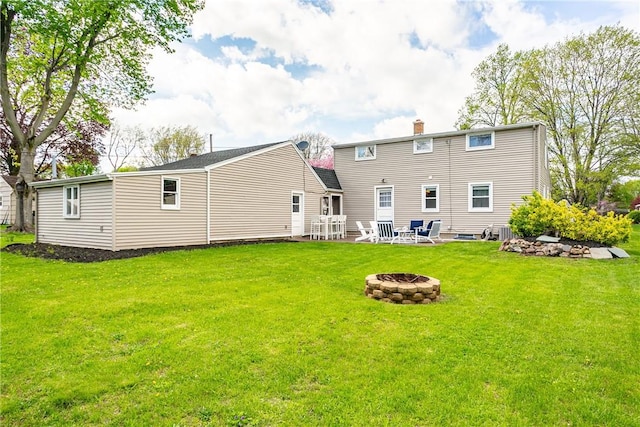 rear view of property with a fire pit, a chimney, and a yard