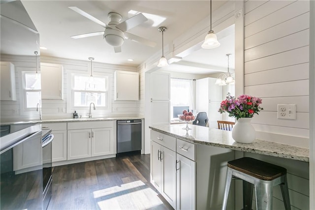 kitchen with stainless steel dishwasher, healthy amount of natural light, a breakfast bar area, and a ceiling fan