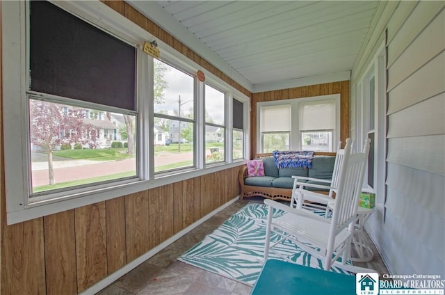 sunroom / solarium featuring wood walls, stone finish flooring, and baseboards
