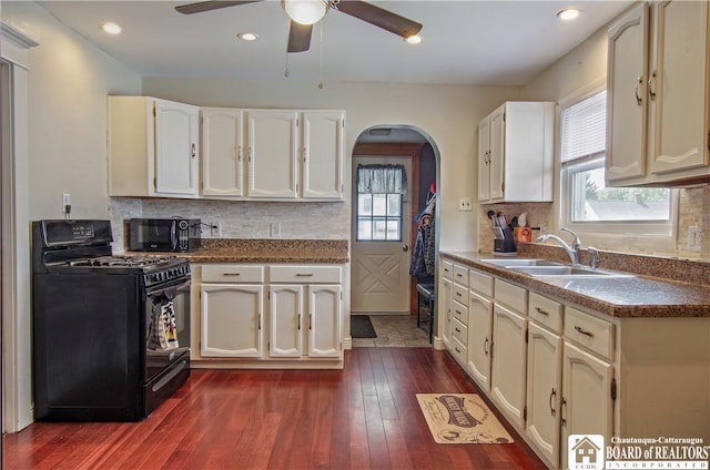 kitchen featuring black appliances, arched walkways, a sink, a ceiling fan, and plenty of natural light