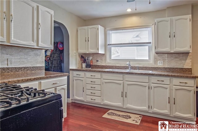 kitchen with a sink, white cabinetry, decorative backsplash, dark wood-style flooring, and black gas range