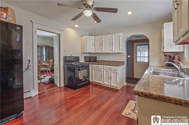 kitchen with black appliances, a sink, arched walkways, dark wood finished floors, and a ceiling fan