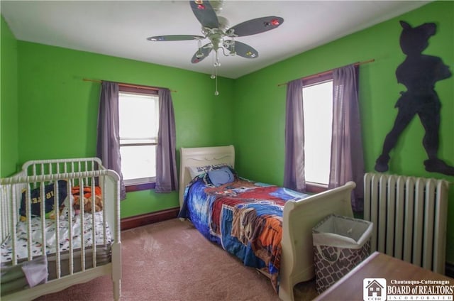 carpeted bedroom featuring radiator, a ceiling fan, and baseboards