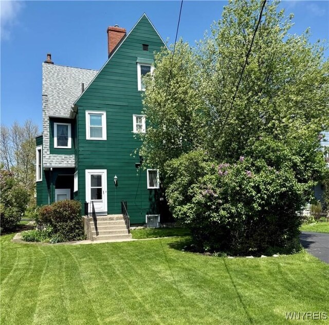 47 Beard Ave, Buffalo, NY 14214 - back of house with a yard, a chimney, central AC unit, and roof with shingles
