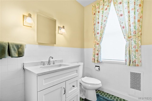 47 Beard Ave, Buffalo, NY 14214 - bathroom featuring tile walls, vanity, toilet, a wainscoted wall, and tile patterned flooring
