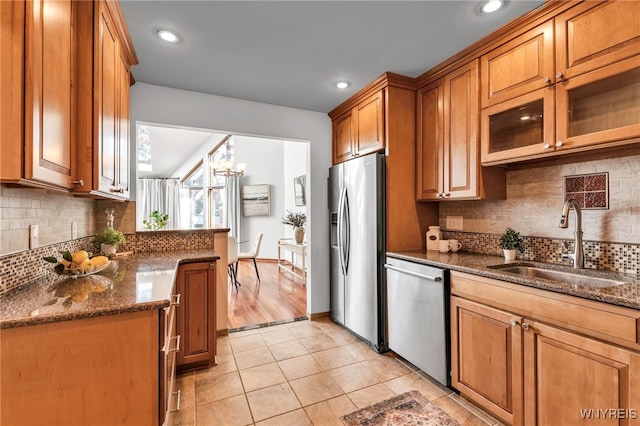 20 Harbour Pointe, Buffalo, NY 14202 - kitchen with stainless steel appliances, a sink, brown cabinetry, light tile patterned floors, and dark stone countertops