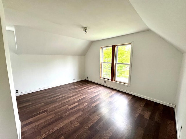 additional living space featuring lofted ceiling, dark wood-style floors, and baseboards