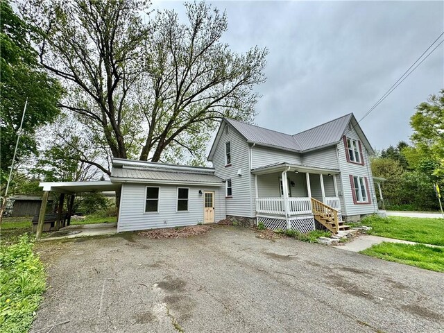 view of home's exterior featuring a porch, driveway, and metal roof